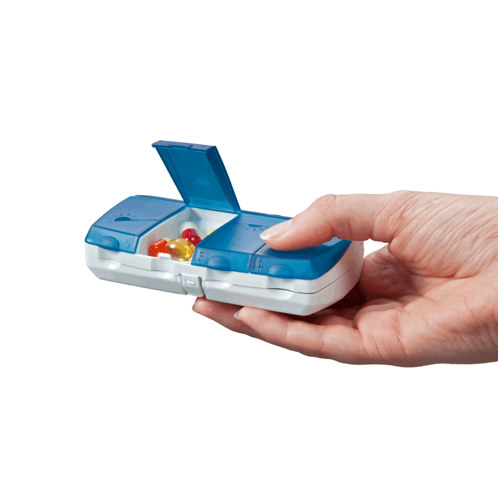 Pilulier journalier Pilbox Daily bleu tenu par une main avec une case ouverte contenant des gélules