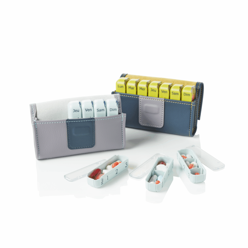 2 petits piluliers gris clair et gris foncé ouverts avec 3 modules posés devant et ouverts avec des médicaments dedans